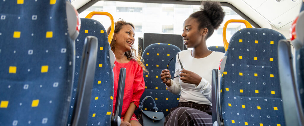 Bilde av to passasjerer som prater sammen på bussen.