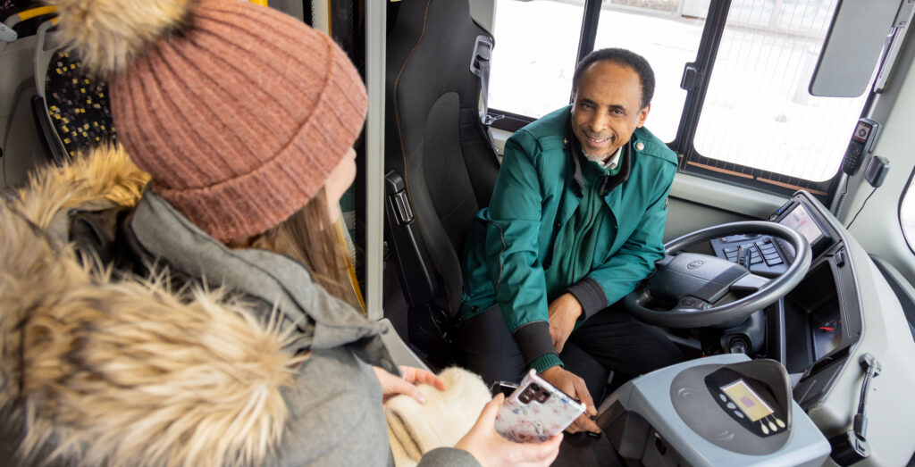 Bilde av passasjer som viser mobilbillett til sjåfør på bussen.